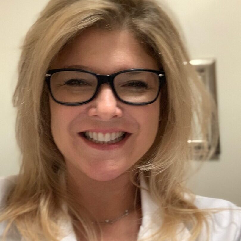 Smiling woman wearing glasses and white coat