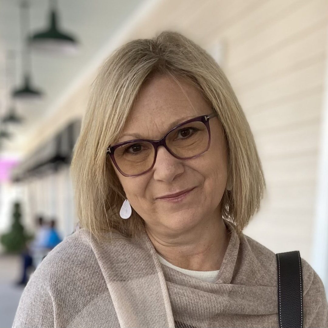 Woman wearing glasses and beige scarf smiling