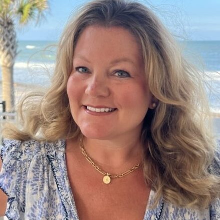 Blonde woman smiling at beach with necklace